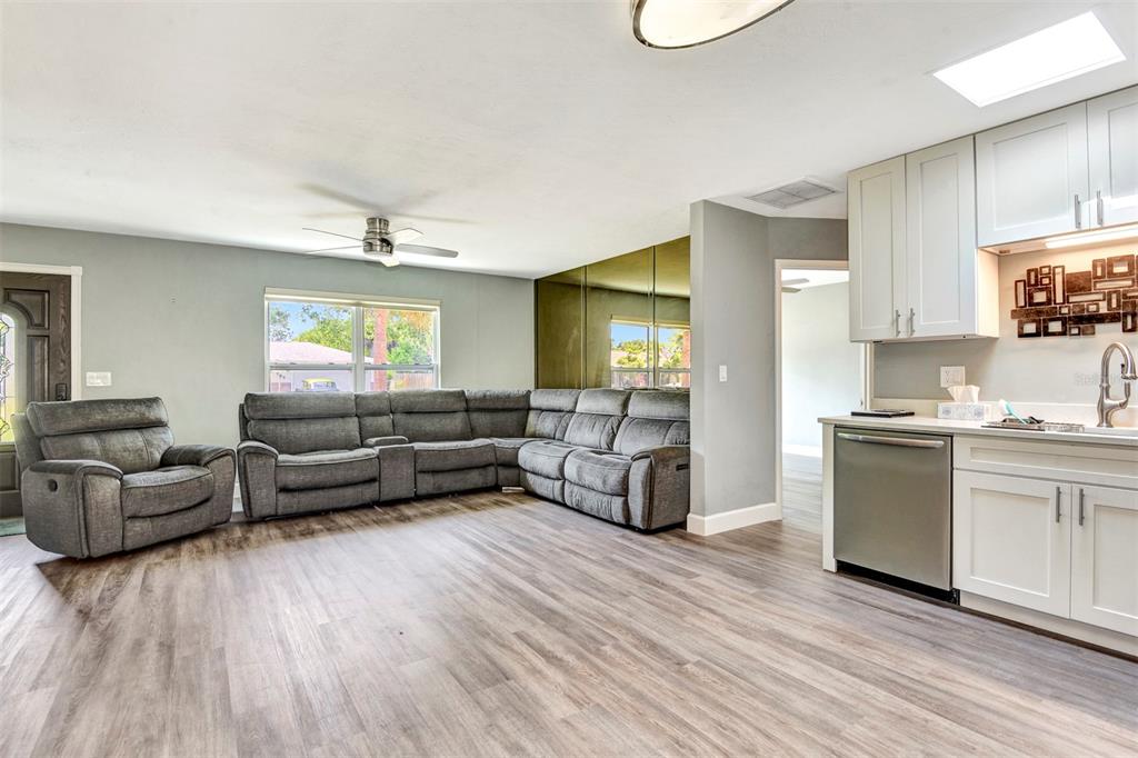 A living room with gray flooring and furniture connects to a kitchen with white cabinets — 781 LITTLE PINE DRIVE, SOUTH DAYTONA, FL