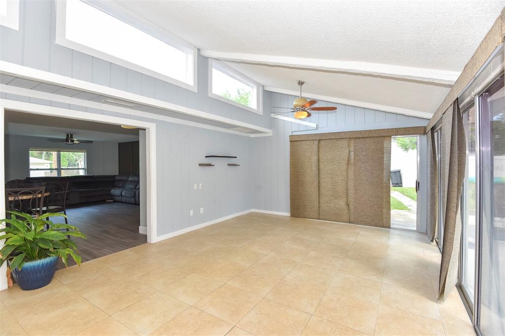 A sunroom with light blue paneled walls, tile flooring, and sliding glass doors — 781 LITTLE PINE DRIVE, SOUTH DAYTONA, FL
