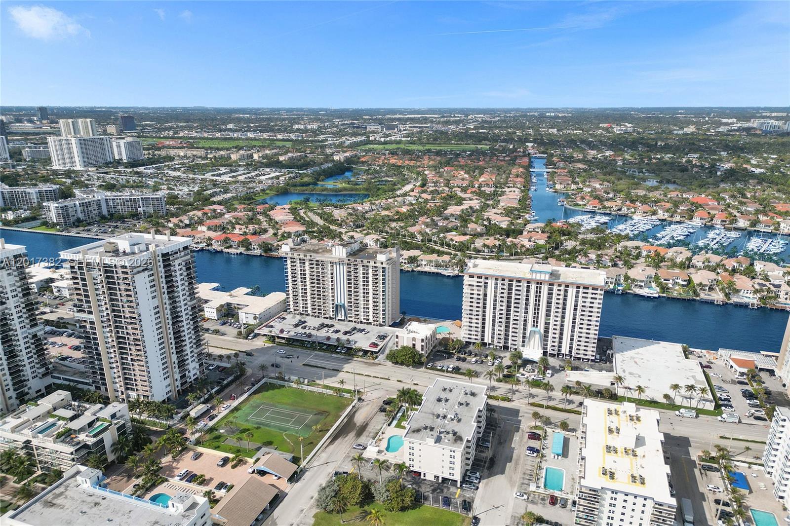 An aerial view shows multiple high-rise apartment buildings, a tennis court, and a canal — 1600 S Ocean Dr # 16B, Hollywood FL 33019, HOLLYWOOD, FL