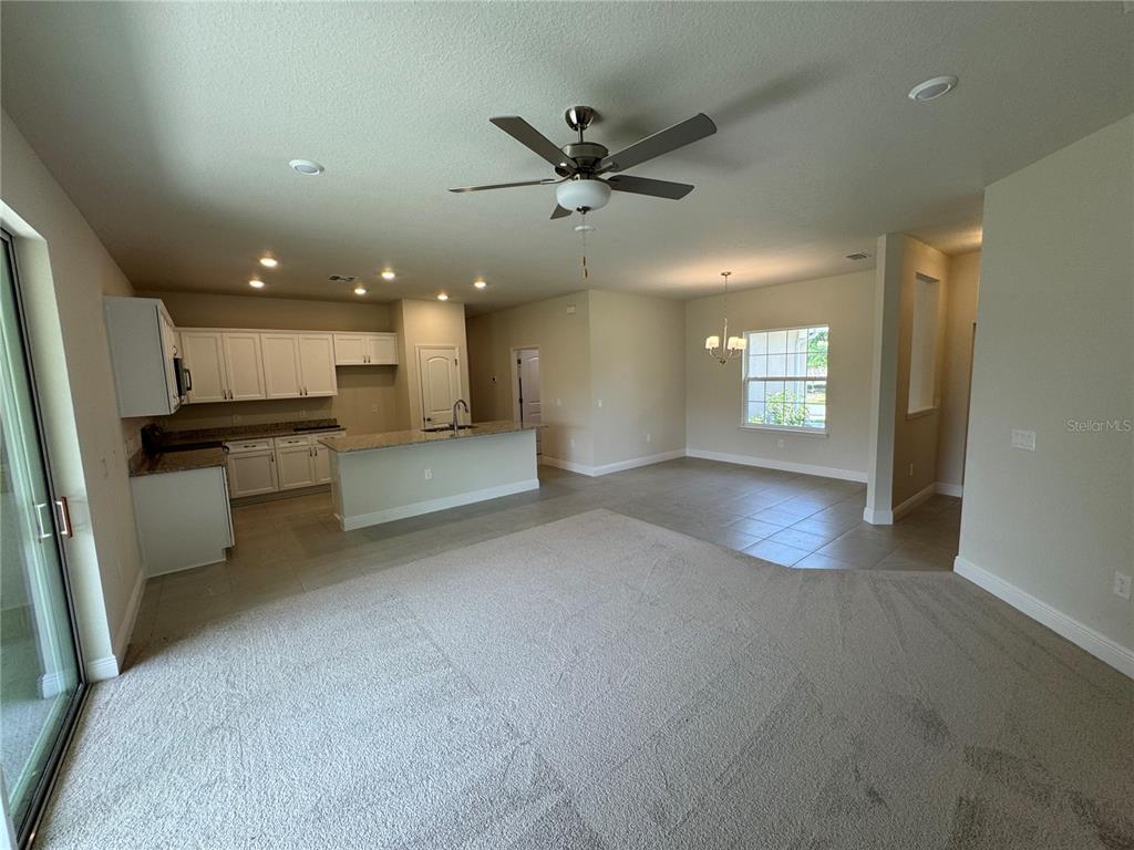 An open-concept living area features a kitchen with white cabinets, granite countertops, and carpeted flooring — 5874 FERENDINA STREET, NORTH PORT, FL
