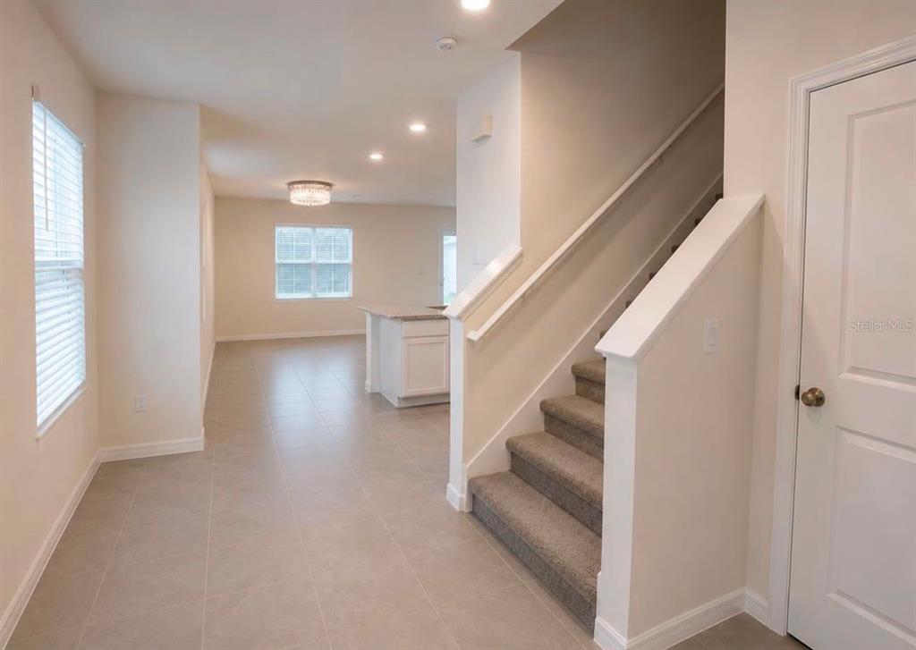 An interior view shows a tiled entryway leading to a carpeted staircase and kitchen area — 35348 SPRUCE KNOB COURT, DADE CITY, FL