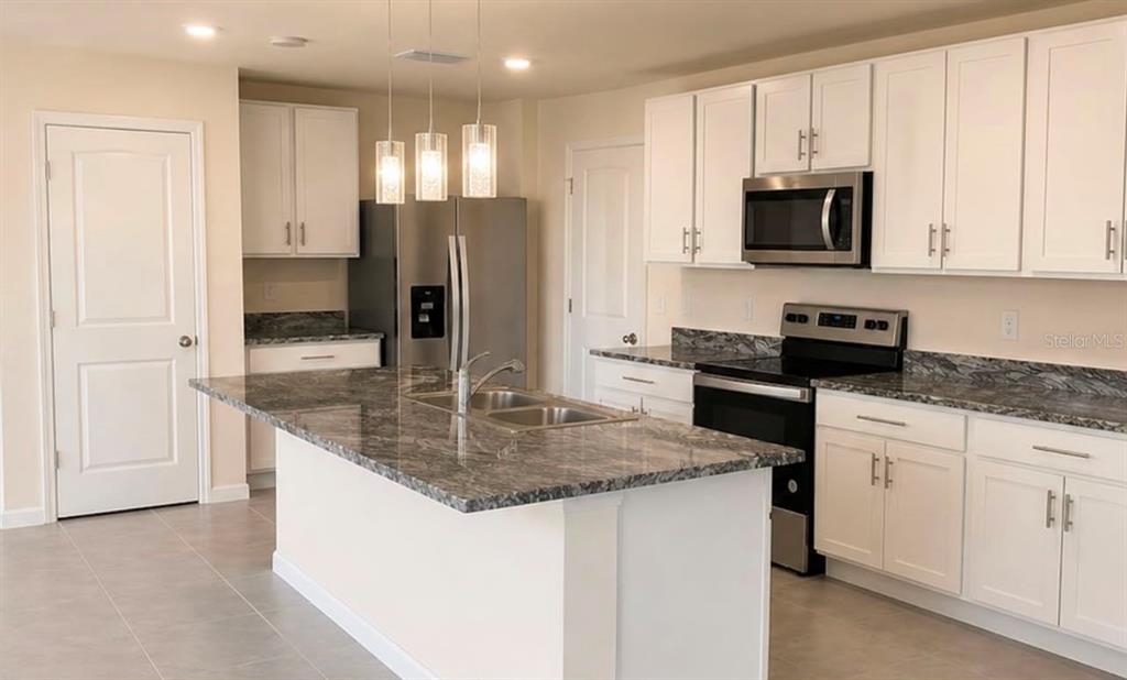 A kitchen features white cabinets, granite countertops, a center island, and stainless steel appliances — 35348 SPRUCE KNOB COURT, DADE CITY, FL