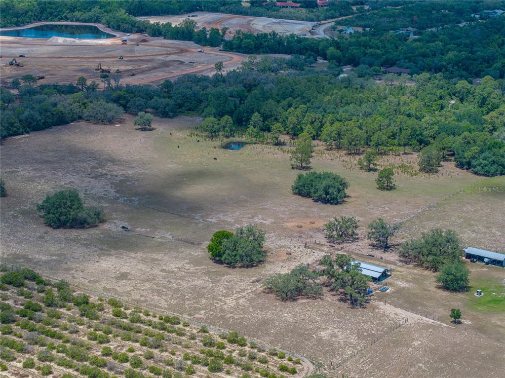 An aerial view shows a rural property with a pasture, small pond, and outbuildings — 10790 JIM EDWARDS ROAD, HAINES CITY, FL