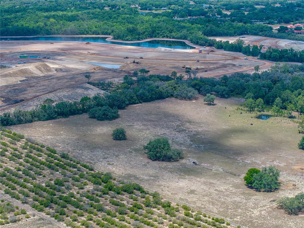 An aerial view shows a large pasture, an orchard, and an adjacent construction site — 10790 JIM EDWARDS ROAD, HAINES CITY, FL