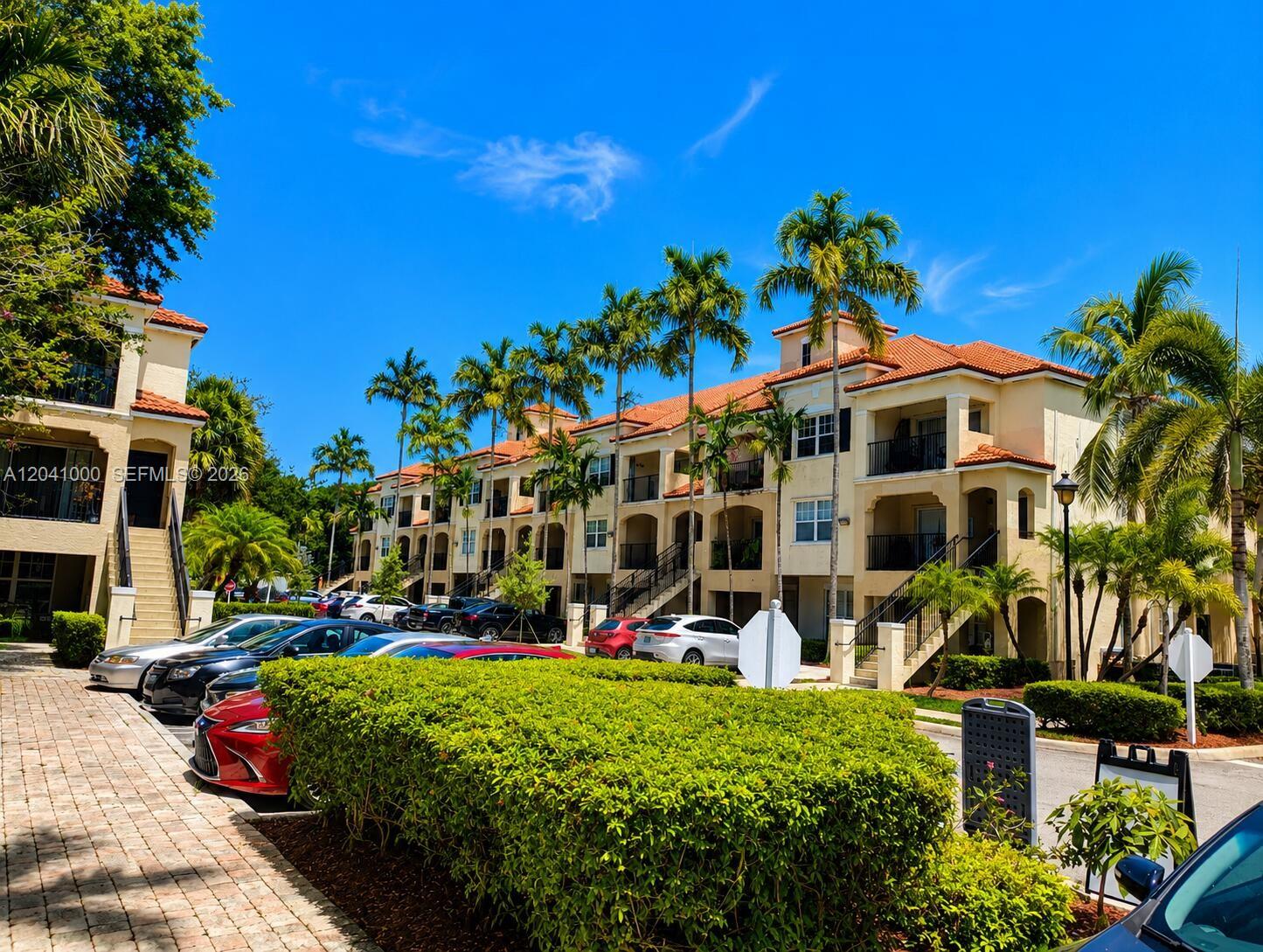A multi-story apartment building with a tiled roof and palm trees in a parking lot — 5980 W Sample Rd # 308, Coral Springs FL 33067, CORAL SPRINGS, FL