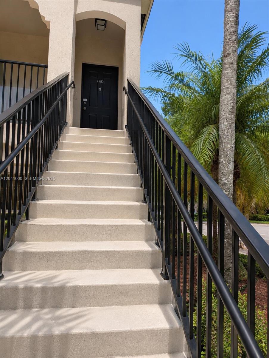 A set of concrete stairs with black metal railings leads up to a black door — 5980 W Sample Rd # 308, Coral Springs FL 33067, CORAL SPRINGS, FL