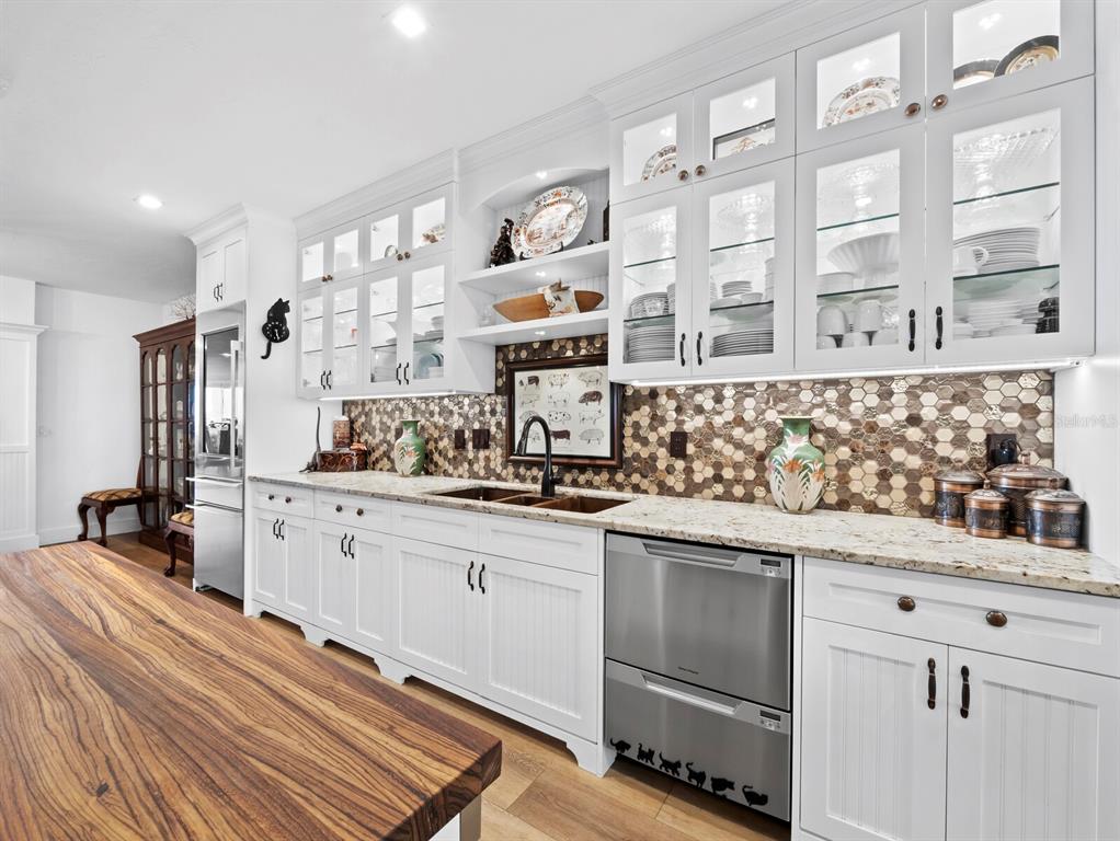 A kitchen features white cabinetry, a wood-topped island, and a brown hexagonal tile backsplash — 340 GULF OF MEXICO DRIVE UNIT 112, LONGBOAT KEY, FL