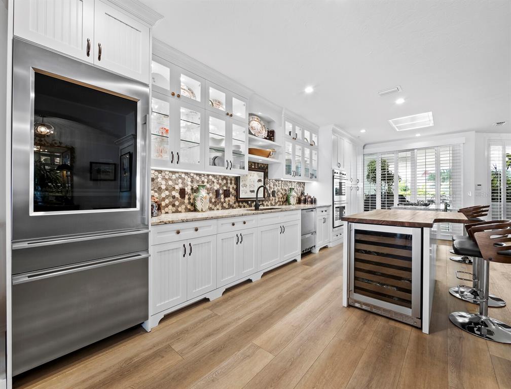 A modern kitchen features white cabinetry, stainless steel appliances, a wood-topped island, and wood flooring — 340 GULF OF MEXICO DRIVE UNIT 112, LONGBOAT KEY, FL