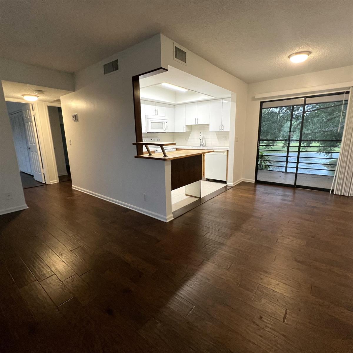A kitchen with white cabinets and a breakfast bar overlooks a living area with flooring — 4205 Oak Terrace Drive # 4205, FL 33463, FL