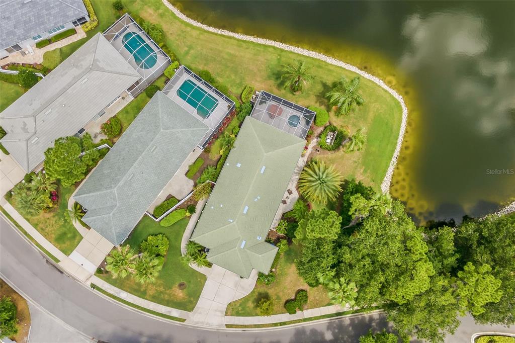 An aerial view shows two suburban houses with swimming pools situated along a curved lake — 8669 54TH AVENUE CIRCLE E, BRADENTON, FL
