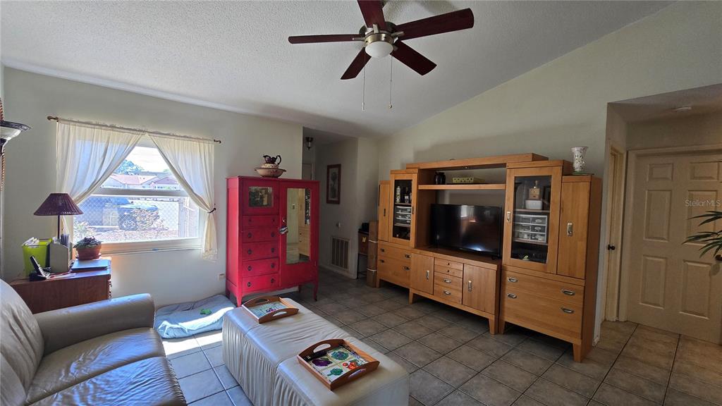 A living room features a large wooden entertainment center, a red cabinet, and tile flooring — 4628 ASHBERRY DRIVE, SARASOTA, FL