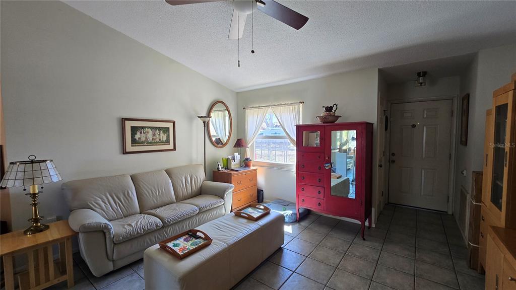 A living room features a beige sofa, a red cabinet, and tile flooring — 4628 ASHBERRY DRIVE, SARASOTA, FL