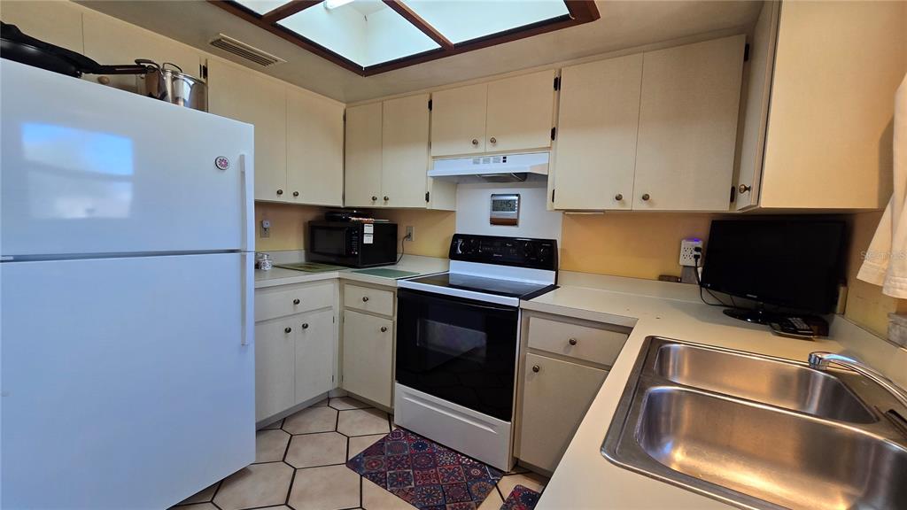 A kitchen features white cabinetry, a white refrigerator, a black stove, and a double sink — 4628 ASHBERRY DRIVE, SARASOTA, FL
