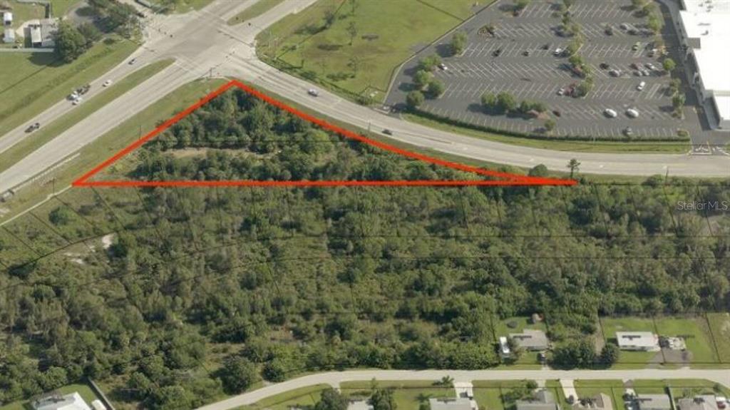 An aerial view shows a triangular, wooded plot of land bordered by roads and buildings — 5682 DUNCAN ROAD, PUNTA GORDA, FL