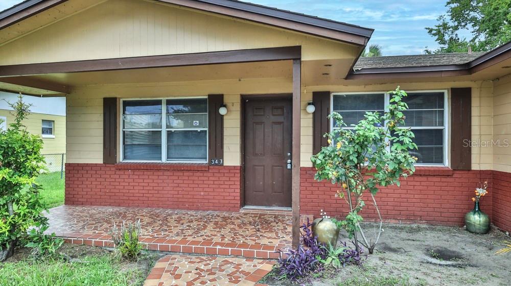 The exterior of a single-story house features a brick facade, a tiled porch, and shutters — 347 PLEASANT STREET, DAYTONA BEACH, FL