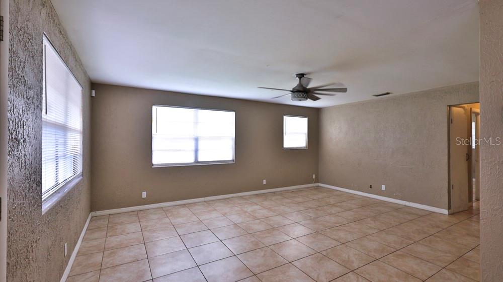 An empty room features tan walls, a ceiling fan, and light-colored square floor tiles — 347 PLEASANT STREET, DAYTONA BEACH, FL