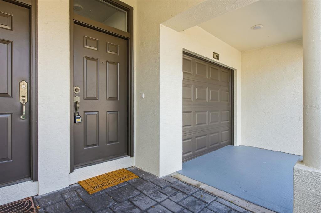 The exterior entrance features a brown front door, a garage door, and a welcome mat — 1027 NORMANDY TRACE ROAD, TAMPA, FL