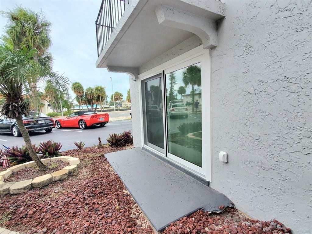 A concrete patio sits outside a sliding glass door on the side of a building — 8151 BLIND PASS ROAD UNIT 3, ST PETE BEACH, FL