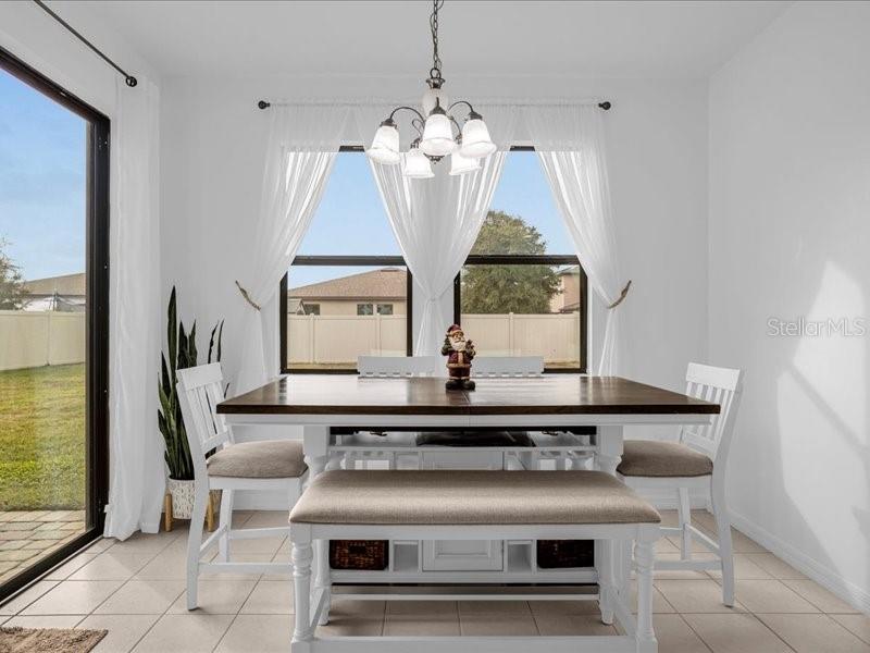 A dining room features a wooden table, white chairs, a bench, and a chandelier — 1020 UMBRIA LANE, ST CLOUD, FL