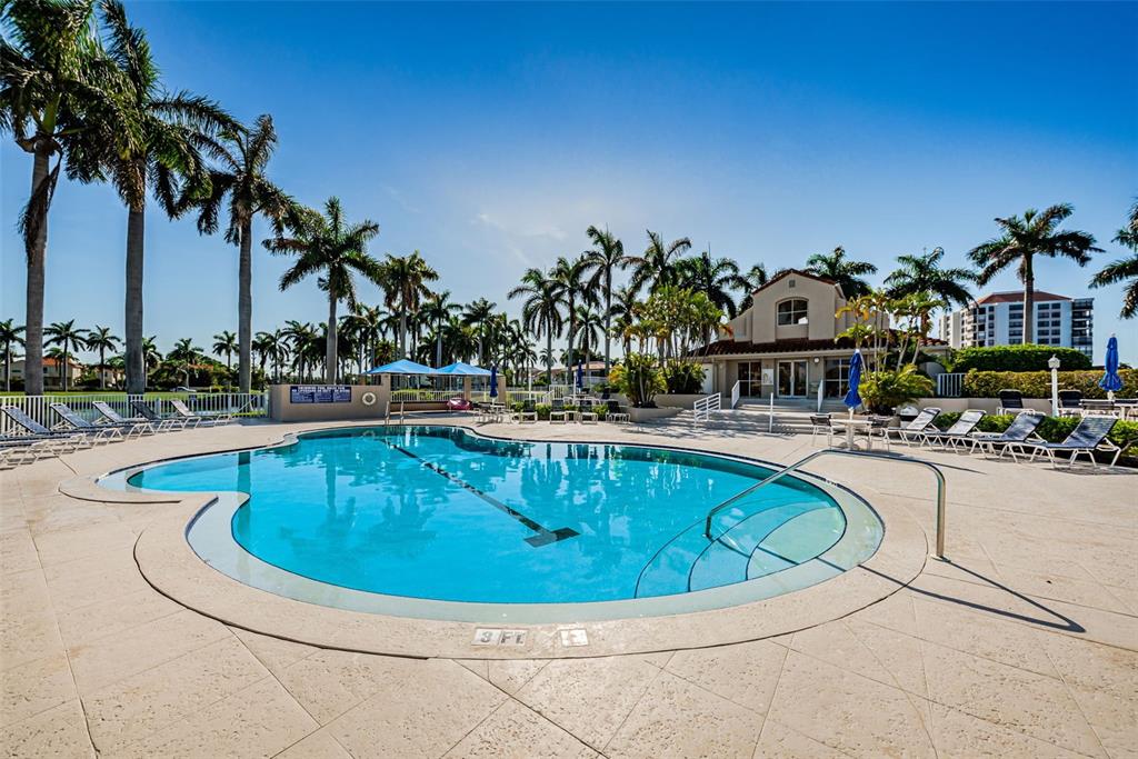A swimming pool with a shallow entry area is surrounded by palm trees and lounge chairs — 6000 BAHIA DEL MAR CIRCLE UNIT 130, ST PETERSBURG, FL