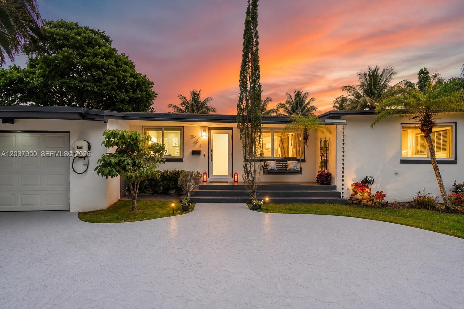 A single-story house with a white exterior, a paved driveway, and a sunset sky — 351 NE 117th St, Miami FL 33161, MIAMI, FL