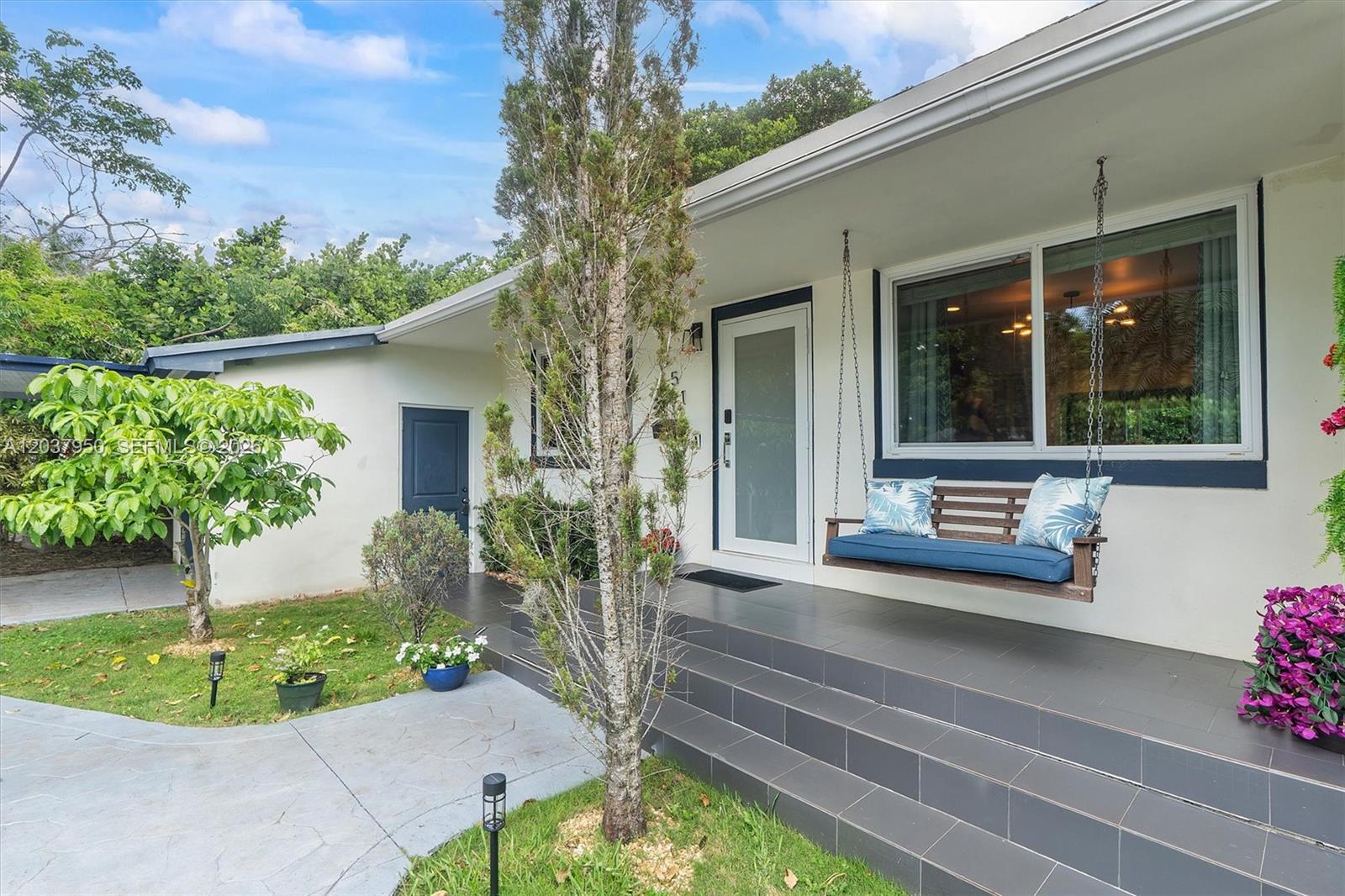 A house exterior features a tiled porch with a hanging bench swing and steps — 351 NE 117th St, Miami FL 33161, MIAMI, FL