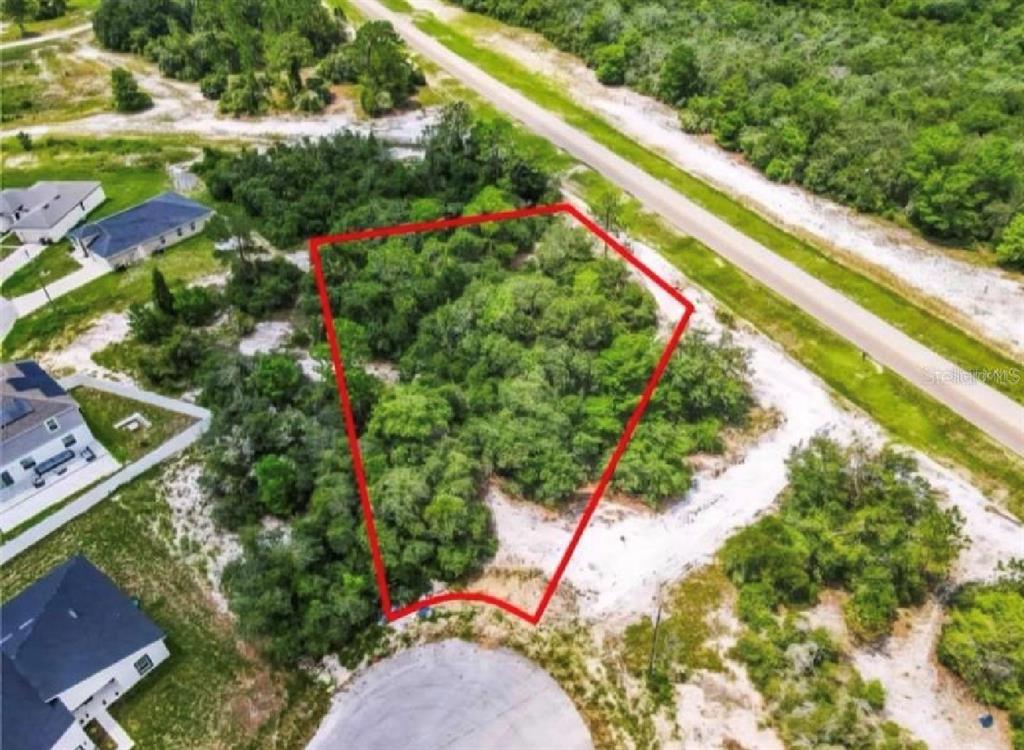 An aerial view shows a vacant, wooded residential lot outlined in red near a cul-de-sac — 612 AMAZON PLACE, KISSIMMEE, FL