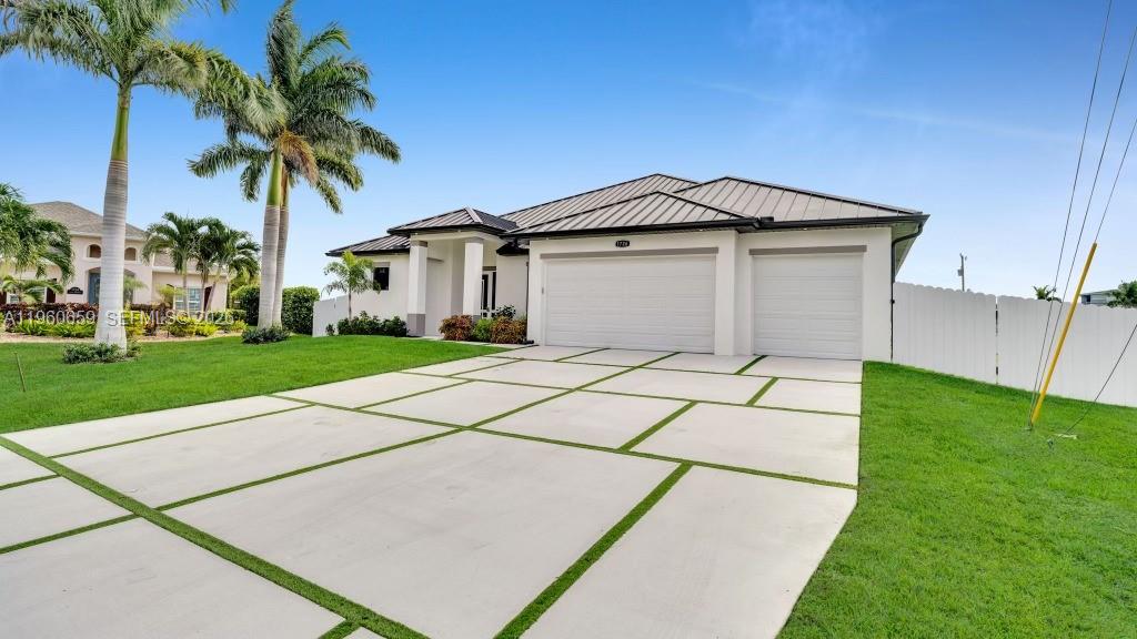 A single-story house with a metal roof, three-car garage, and a grid-patterned concrete driveway — 1726 SW 36TH TER,, Cape Coral FL 33914, CAPE CORAL, FL