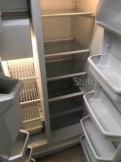 An open refrigerator interior with glass shelves, wire racks, and multiple door storage bins — 417 SOUTHERN PECAN CIRCLE UNIT 204, WINTER GARDEN, FL