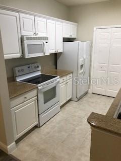 A kitchen with white cabinets, stainless steel appliances, and tan countertops — 417 SOUTHERN PECAN CIRCLE UNIT 204, WINTER GARDEN, FL