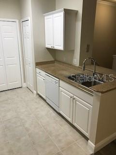 A kitchen features white cabinets, a dishwasher, a double sink, and tan countertops — 417 SOUTHERN PECAN CIRCLE UNIT 204, WINTER GARDEN, FL