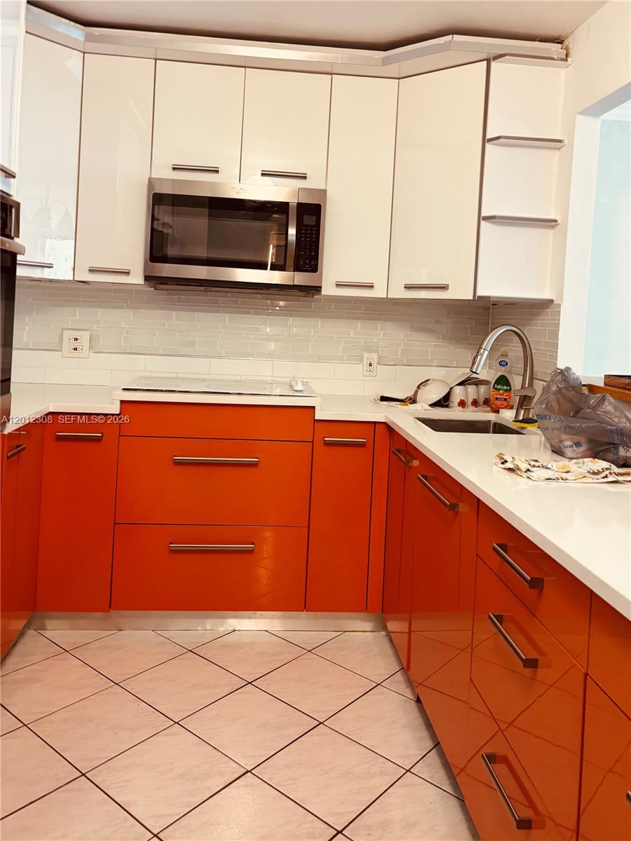 A kitchen features orange lower cabinets, white upper cabinets, and white countertops — 1817 S Ocean Dr # 622, Hallandale Beach FL 33009, HALLANDALE BEACH, FL