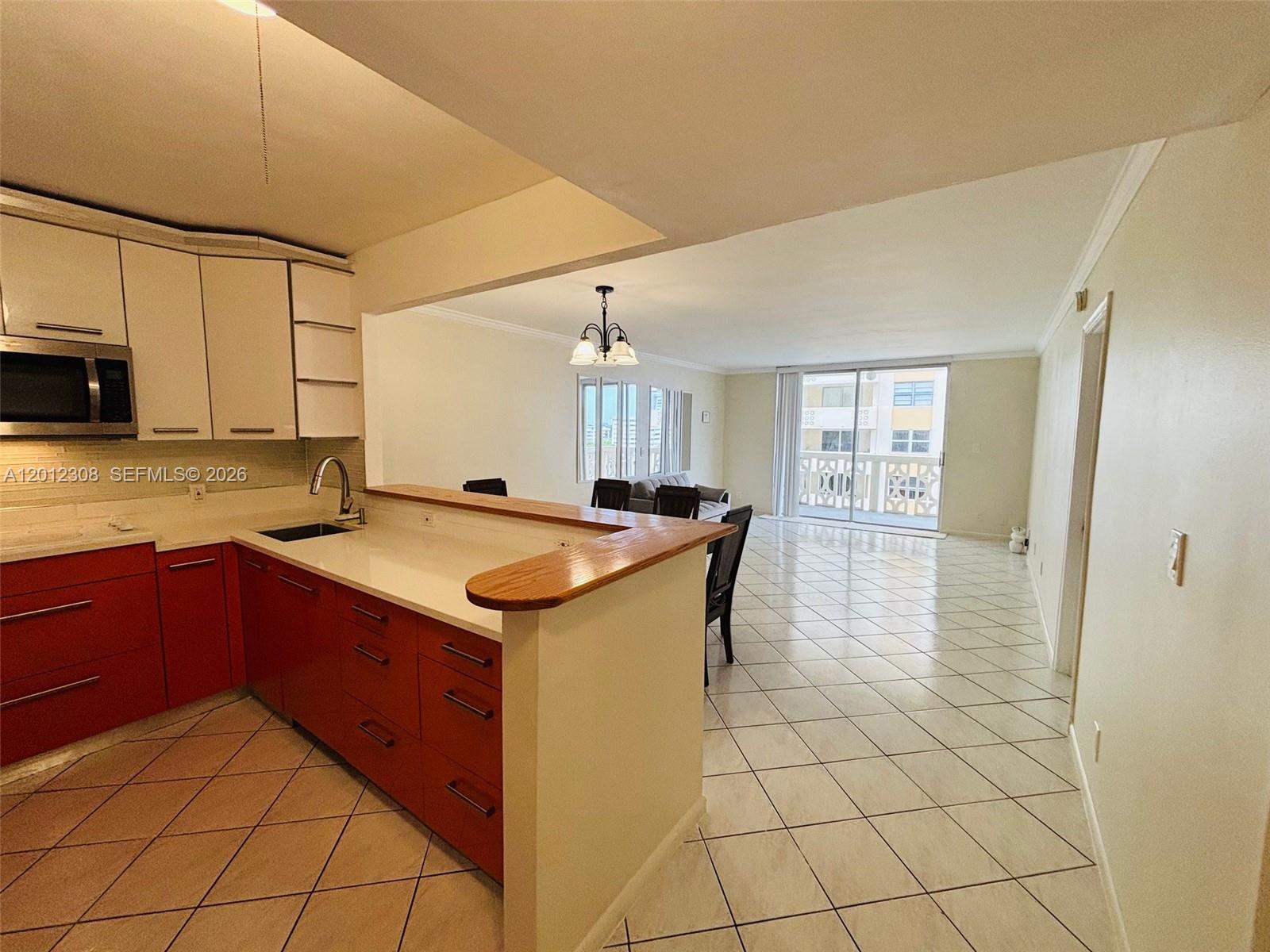 A kitchen with red lower cabinets and white upper cabinets opens into a tiled living area — 1817 S Ocean Dr # 622, Hallandale Beach FL 33009, HALLANDALE BEACH, FL