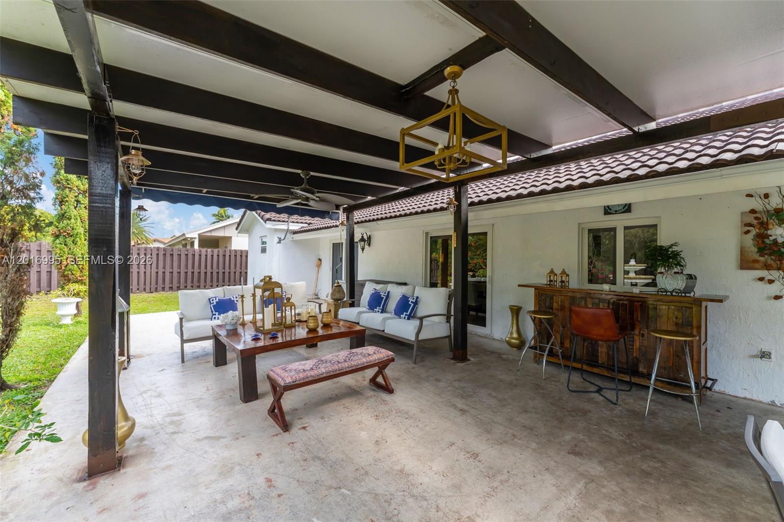 A covered outdoor patio features a seating area, a wooden bar, and dark wooden beams — 15325 SW 54th Ter, Miami FL 33185, MIAMI, FL