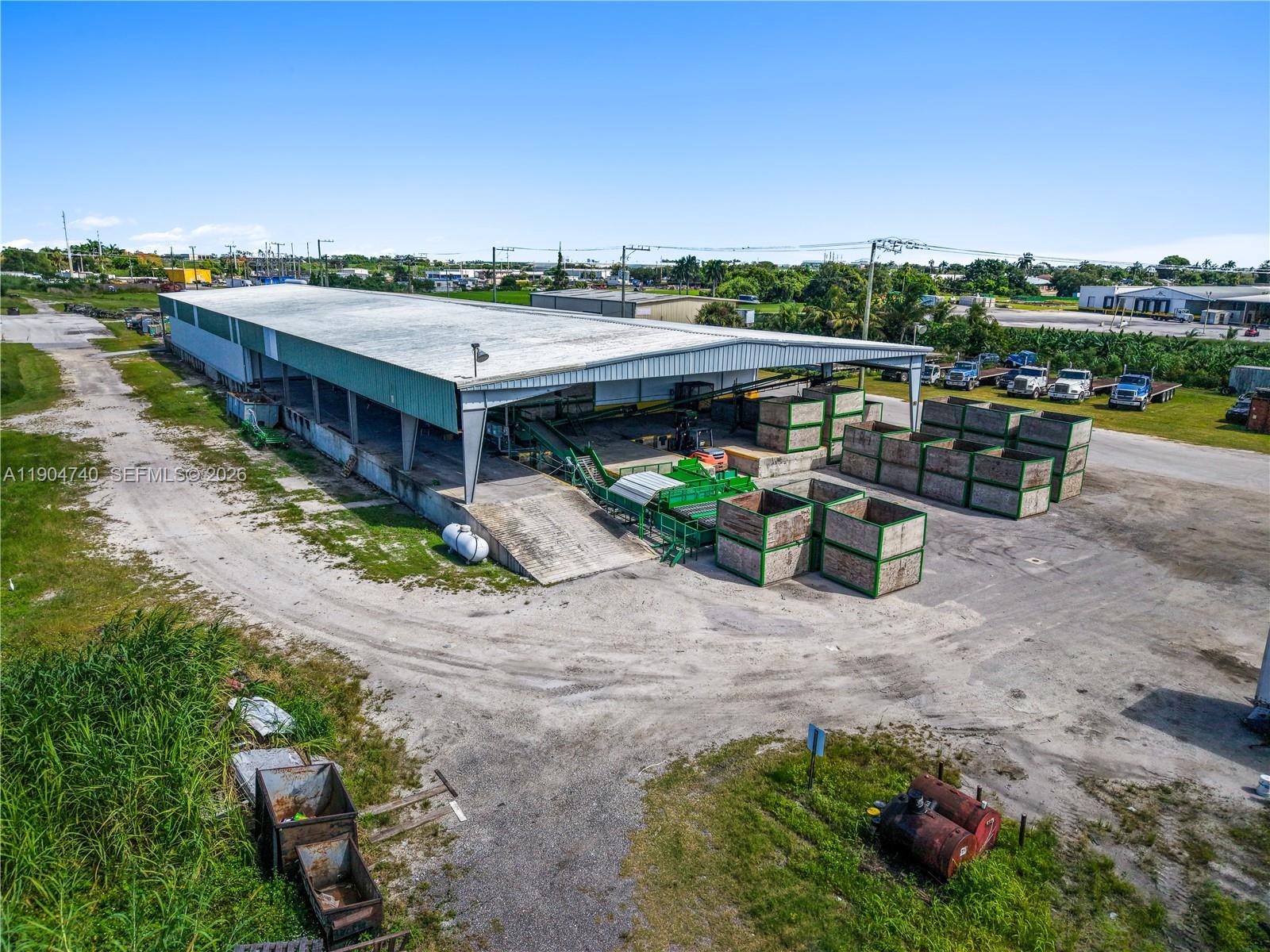 An aerial view shows an industrial warehouse with open bays, sorting equipment, and large storage crates — 901 NW 9th St, Belle Glade FL 33430, BELLE GLADE, FL