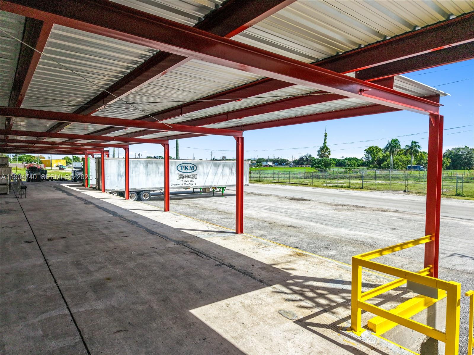A covered loading dock with red steel beams, concrete flooring, and a yellow safety railing — 901 NW 9th St, Belle Glade FL 33430, BELLE GLADE, FL