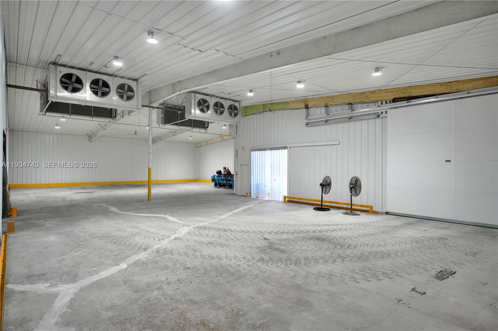 A large, empty industrial warehouse space features concrete floors, metal walls, and overhead cooling units — 901 NW 9th St, Belle Glade FL 33430, BELLE GLADE, FL