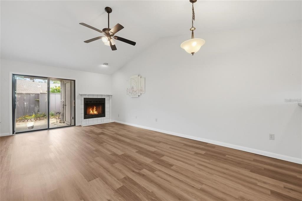 A living room with wood-look flooring, a fireplace, a ceiling fan, and sliding glass doors — 3741 NW 56TH LANE, GAINESVILLE, FL