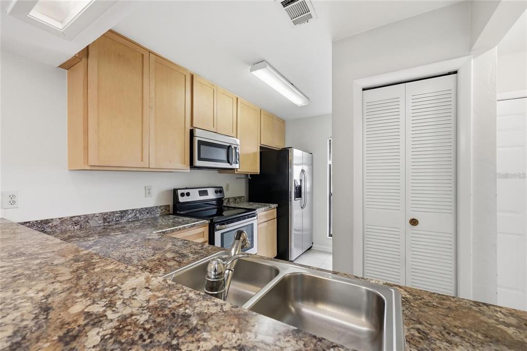 A kitchen features light wood cabinets, granite-look countertops, stainless steel appliances, and white louvered doors — 3741 NW 56TH LANE, GAINESVILLE, FL