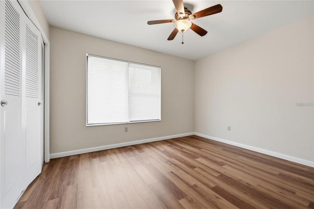 An empty bedroom features wood-look flooring, a ceiling fan, and white louvered closet doors — 3741 NW 56TH LANE, GAINESVILLE, FL