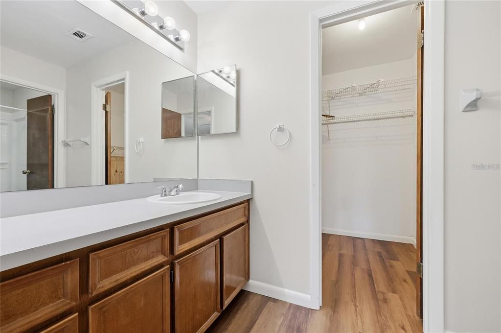 A bathroom features a wooden vanity with a white countertop, a mirror, and an adjacent closet — 3741 NW 56TH LANE, GAINESVILLE, FL