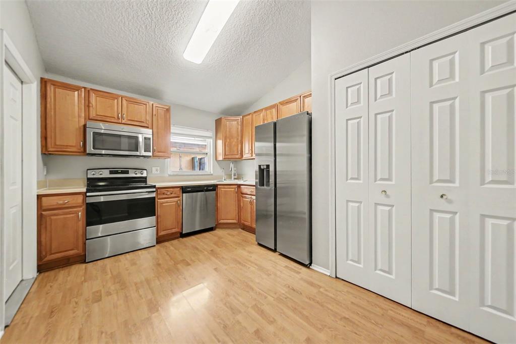 A kitchen features light wood cabinets, stainless steel appliances, and light-colored wood-look flooring — 1077 SUGARBERRY TRAIL, OVIEDO, FL