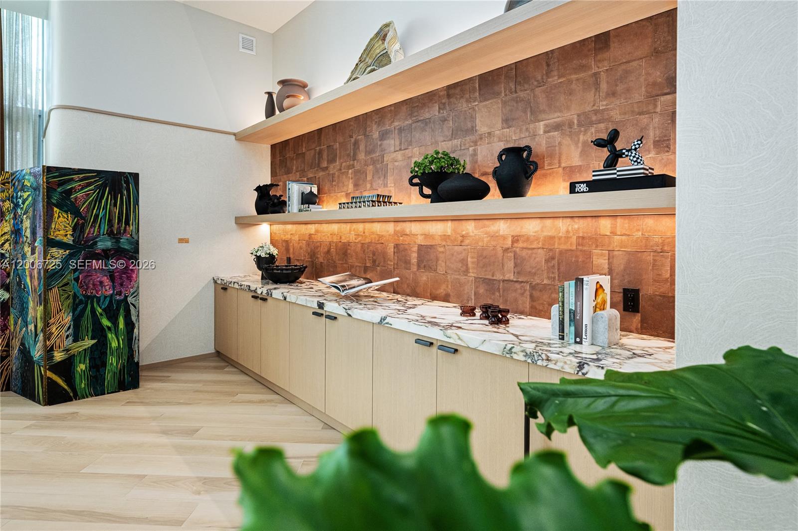 A modern room features light wood cabinetry, marble countertops, and illuminated shelves against tiled walls — 77 SE 5 # 1505, Miami FL 33131, MIAMI, FL
