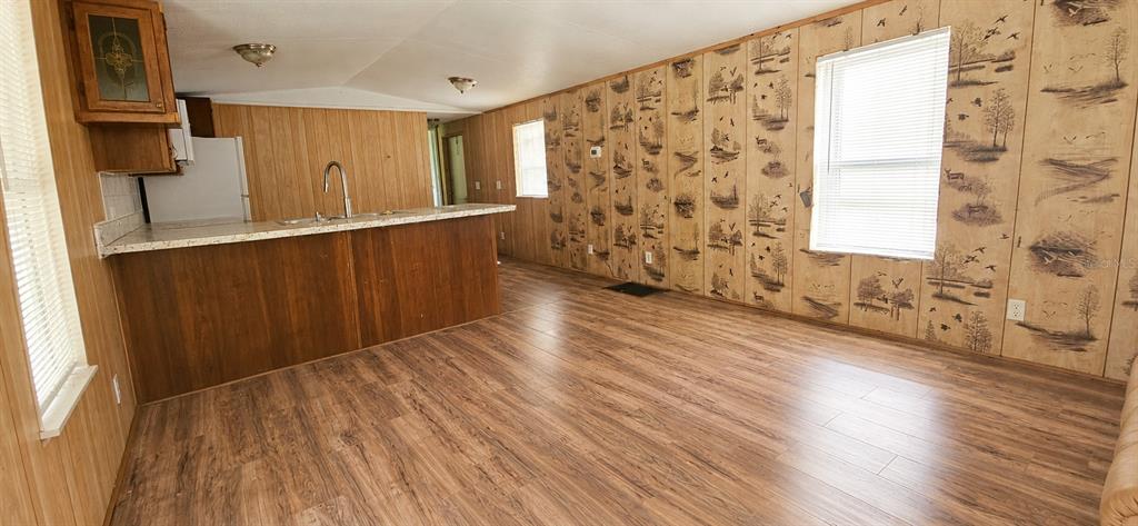 A kitchen with a breakfast bar and wood-paneled walls opens into a living area — 706 DAVID AVENUE, INTERLACHEN, FL