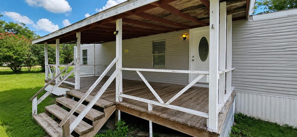 A wooden porch with white railings and stairs attached to the side of a mobile home — 706 DAVID AVENUE, INTERLACHEN, FL
