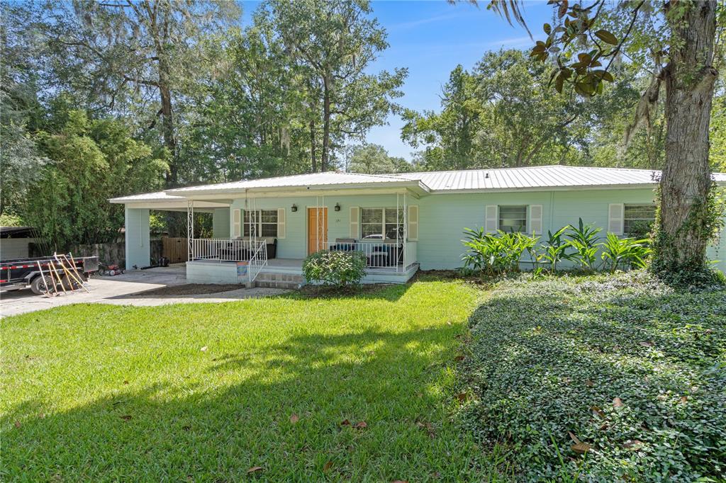 A light green, single-story house features a metal roof, a front porch, and a carport — 121 NW 29TH ST, GAINESVILLE, FL