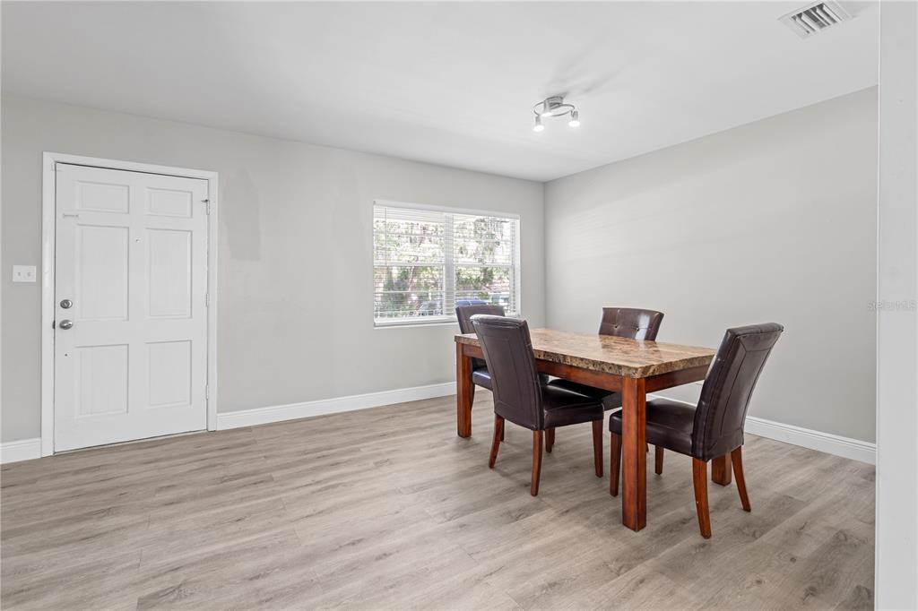 A dining room with light gray walls, wood-look flooring, a window, and a dining set — 121 NW 29TH ST, GAINESVILLE, FL
