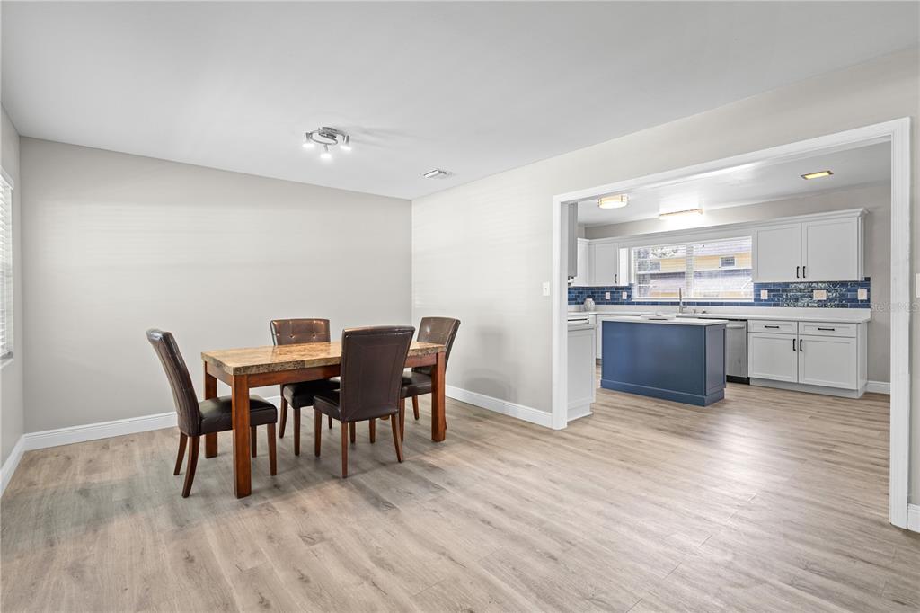 A dining area with a wood table and chairs opens into a kitchen with blue cabinetry — 121 NW 29TH ST, GAINESVILLE, FL