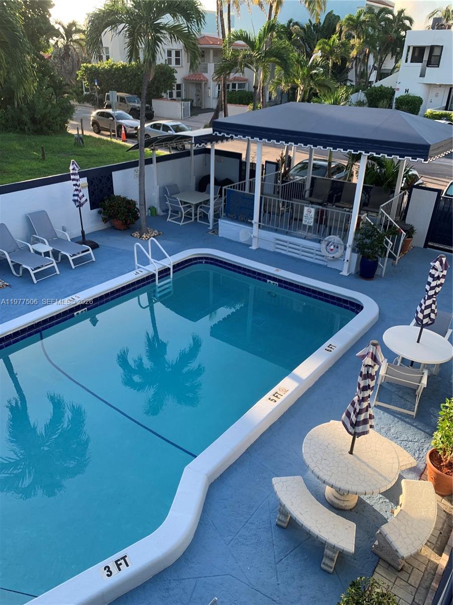 An elevated view of a swimming pool area with lounge chairs, tables, and umbrellas — 322 Taylor St # 2D, Hollywood FL 33019, HOLLYWOOD, FL
