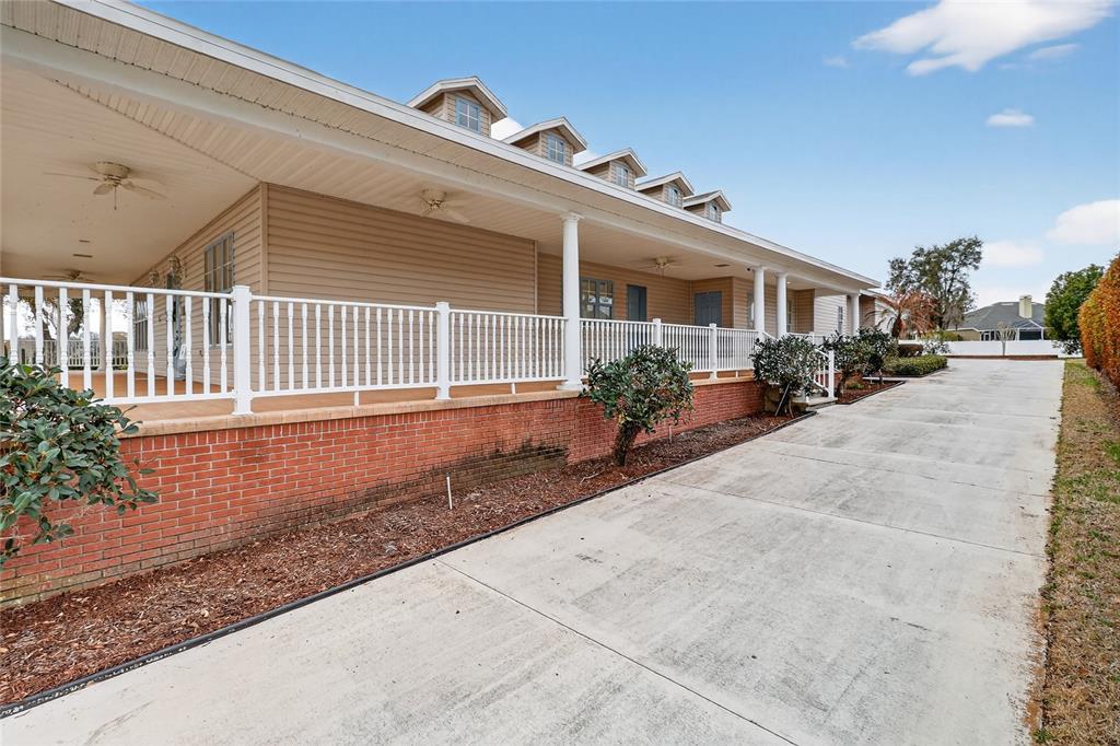 A long, single-story house features a brick foundation, tan siding, and a covered porch — 2128 LAKE ARIANA BOULEVARD, AUBURNDALE, FL